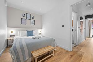 a white bedroom with a bed and a wooden bench at Stunning Luxury Townhouse in Centre of Manchester in Manchester