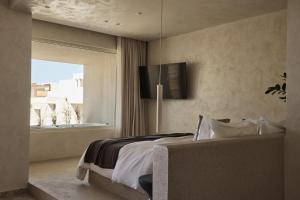 a bedroom with a large bed and a window at Uzenie All Suites Boutique Resort - Adults Only in Adelianos Kampos