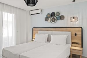 a white bedroom with a white bed with white pillows at White Olive Marine Aquapark in Tigaki