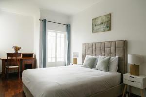 a bedroom with a large white bed and a desk at Casa do Sol Wellness Villa in Óbidos