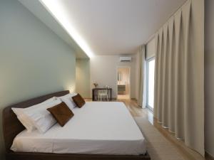 a bedroom with a bed with white sheets and a window at Domus Eterea in Marsala