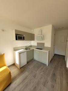 a small kitchen with white cabinets and a yellow couch at Studio Saint Georges de Didonne in Saint-Georges-de-Didonne +2 photos