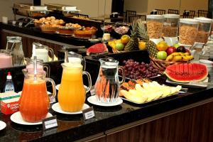 a buffet with fruit and juice and other food at JF Hotel Nova Aliança in Ribeirão Preto