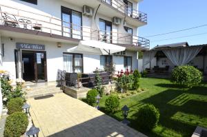 a building with a patio and an umbrella at Vila Bliss in Costinesti