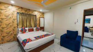 a bedroom with a bed and a blue chair at Agy Hotels in Pune