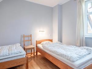 two beds in a room with a chair and a window at Holiday Home Domek Joanna-3 by Interhome in Łeba