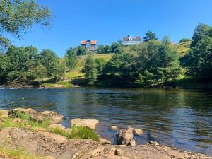 a river with rocks and houses on a hill at Traditional House With Personal Decor in Hauge