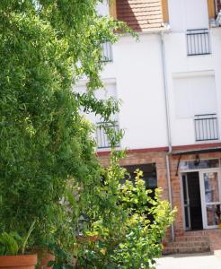 un arbre devant un bâtiment blanc dans l'établissement Emanapartmanok Sárvár, à Sárvár