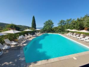 a large swimming pool with chairs and umbrellas at Residence Casa Lama in Castelfranco di Sopra