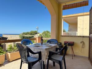 Casa Valentina في توري دي كورساري: طاولة مع كراسي وزجاجة من النبيذ على الفناء