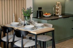 a table with chairs and plates and flowers on it at Solaris Apartamenty in Pobierowo