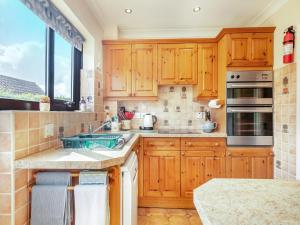 a kitchen with wooden cabinets and a large window at Langford Cottage in Ringstead