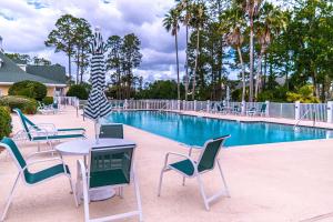 a swimming pool with chairs and tables and a table and chairs at Spacious 3 BR plus SS in Den & screened lanai waterside in Sampson