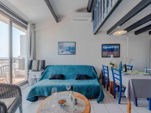 een slaapkamer met een blauw bed en een tafel en stoelen bij Apartment Palmyra-5 by Interhome in Le Barcarès