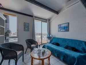een woonkamer met een blauwe bank en een tafel bij Apartment Palmyra-5 by Interhome in Le Barcarès