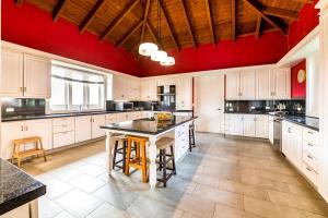 a large kitchen with white cabinets and red walls at Casa Serena in La Romana +26 photos