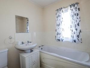 ein weißes Badezimmer mit Waschbecken, Badewanne und Fenster in der Unterkunft Lazy Days in Padstow + 22 Fotos