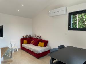 a living room with a red couch with colorful pillows at mini villa neuve moderne proche des plages in Brétignolles-sur-Mer