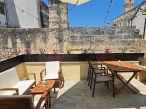 a patio with wooden tables and chairs and a wall at Suite Verdi in Lecce