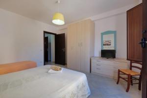 een slaapkamer met een bed, een tv en een stoel bij Noa's in SantʼAnna Arresi