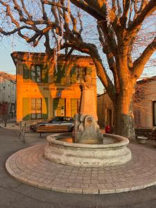 a fountain in front of a building with a tree at Maison village provençal in Éguilles
