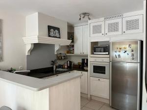 a kitchen with white cabinets and a stainless steel refrigerator at Maison village provençal in Éguilles