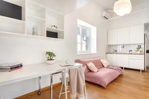 a living room with a pink couch and a table at modern studio apartment in the heart of old city in Ljubljana +7 photos