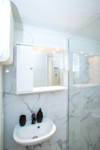 um banheiro branco com uma pia e um espelho em Athens Central Jacuzzi Retreat em Atenas