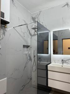 a white bathroom with a shower and a sink at Fusha Apartment in Velipojë
