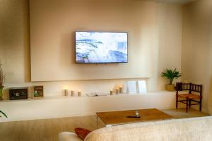 ein Wohnzimmer mit einem Fernseher an der Wand mit Kerzen in der Unterkunft Escapade - Ciné privé, balnéo et jardin in Saint-Ambroix