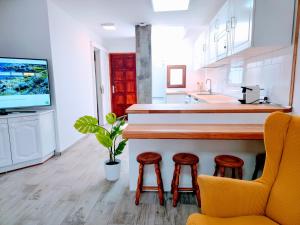 a kitchen with a bar with stools and a tv at VV Duplex Isla Bonita "by henrypole home" in Los Cancajos
