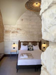 a bedroom with a bed and a stone wall at Dimora Spugnara in Lampedusa