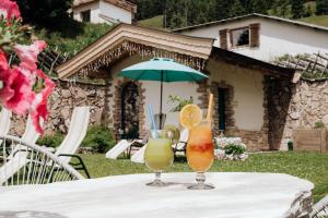 two drinks on a table with an umbrella at Berghotel Ronach in Königsleiten