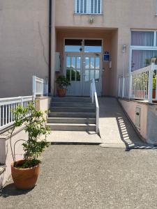 a front door of a building with stairs and a plant at Guest House Regina Mundi in Međugorje