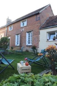 a garden with a table and chairs in front of a building at Au Nid du MONT in Le Mont-Saint-Adrien