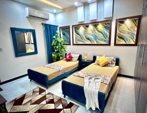 two beds in a room with paintings on the wall at Homely Guest House in Rawalpindi