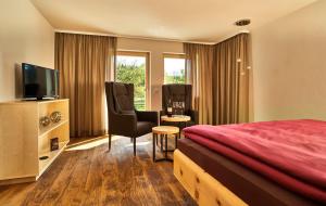 a hotel room with a bed and a chair and a television at Stern Romantik am Hof in Kollnburg