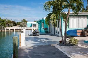 a house with a palm tree next to the water at Reel Deal - Waterfront Pool Home, 76' Dock in Marathon