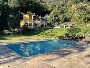 a swimming pool in front of a house at Linda Casa 4qts Piscina Churrasqueira Petrópolis - Venha para a Festa do colono Alemão Bauernfest 2025 in Correas