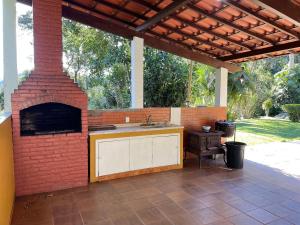 an outdoor kitchen with a brick fireplace in a patio at Linda Casa 4qts Piscina Churrasqueira Petrópolis - Venha para a Festa do colono Alemão Bauernfest 2025 in Correas