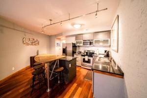 a kitchen with stainless steel appliances and a wooden floor at Downwinder - Waterfront 2-Bedroom, 2-Bathroom Suite at REAL Watersports in Waves