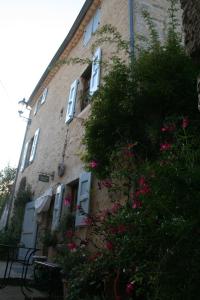 un edificio de ladrillo con flores rosas delante de él en Chambre d'hôtes La Romarine, en Barnave