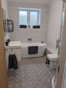 a bathroom with a tub and a sink and a toilet at The Roost at The Gables Farm in Poynton +9 photos
