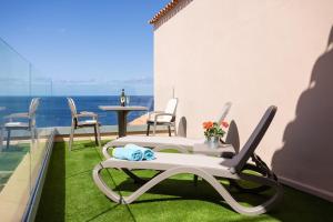 a balcony with chairs and a table and a view of the ocean at Romantic Retreat in Prime Position in Acantilado de los Gigantes
