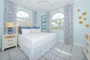 Un dormitorio con una cama blanca y dos ventanas. en Reel Relaxin` - Luxury Waterfront Pool Home, 55' Dock, en Marathon