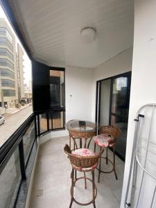 a balcony with a glass table and two chairs at AP BEIRA MAR 6 MINUTOs DO BETO CARRERO in Navegantes +8 photos