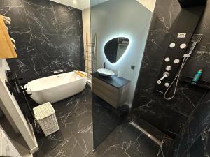 a bathroom with a tub and a sink and a mirror at Superbe appartement moderne in La Valette-du-Var
