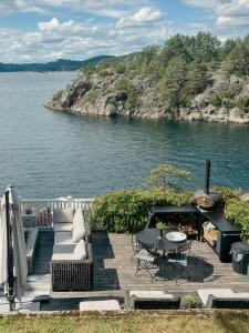 un ponte con un divano e un tavolo vicino all'acqua di Charming Sea Cabin On Fluer By Kragerø a Valle Altre 26 foto