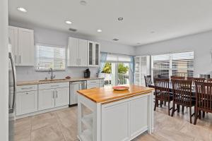 a kitchen with white cabinets and a table and chairs at Tipsy Turtle - Waterfront Pool Home, Direct Atlantic Access! in Marathon
