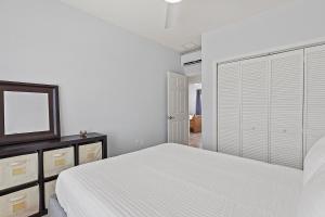 a white bedroom with a bed and a mirror at Tipsy Turtle - Waterfront Pool Home, Direct Atlantic Access! in Marathon